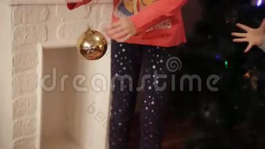 两个微笑的小女孩在家里的新年树上装饰圣诞装饰品。 圣诞树用冷杉锥。 新